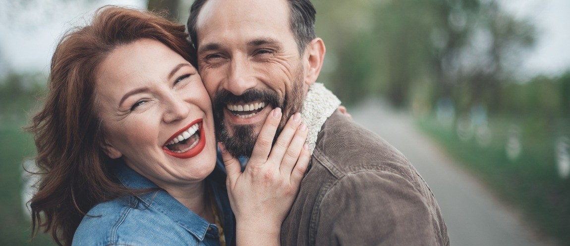Man and woman with healthy smiles after dental implant supported tooth replacement
