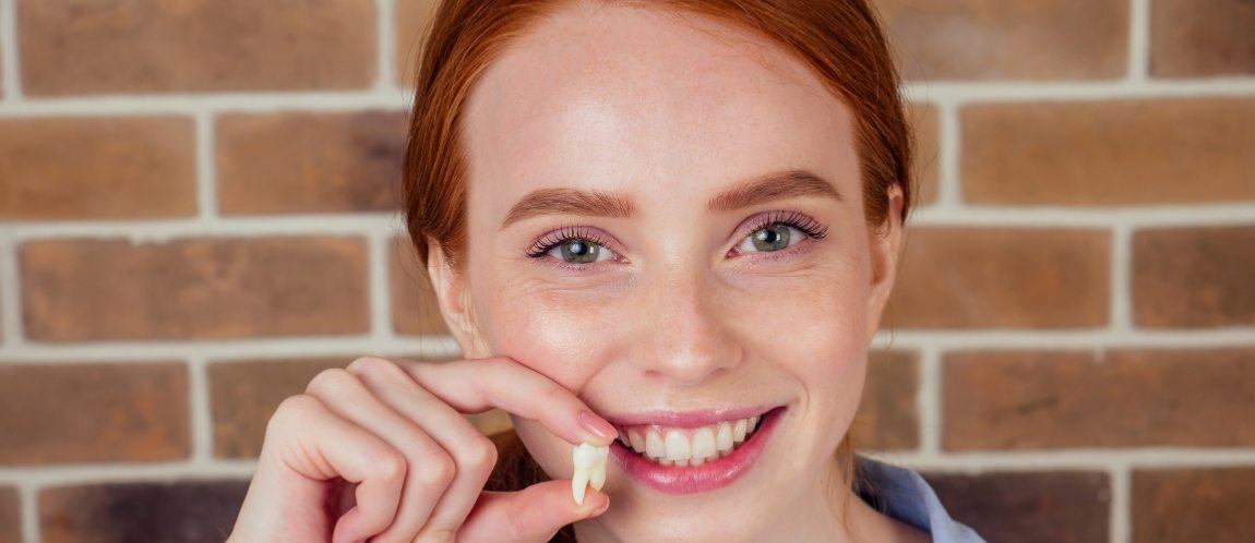 Woman holding up tooth after extraction