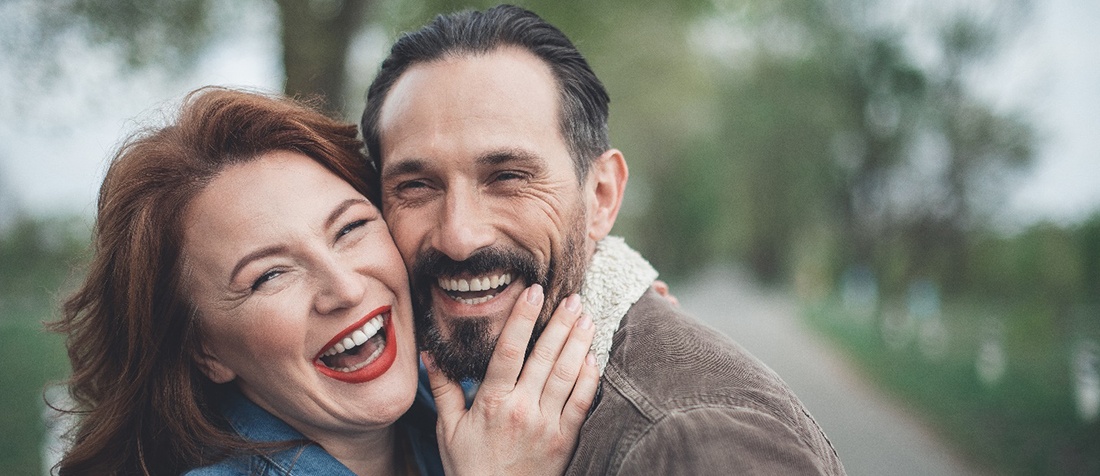 man and woman laughing and holding each other 