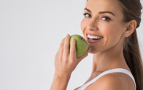 young woman biting into a green apple 