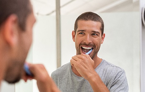 man brushing his teeth in front of a mirror 