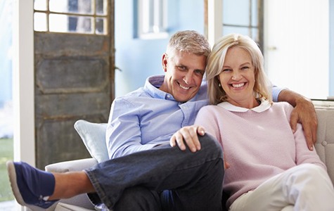 smiling man and woman sitting on a couch 