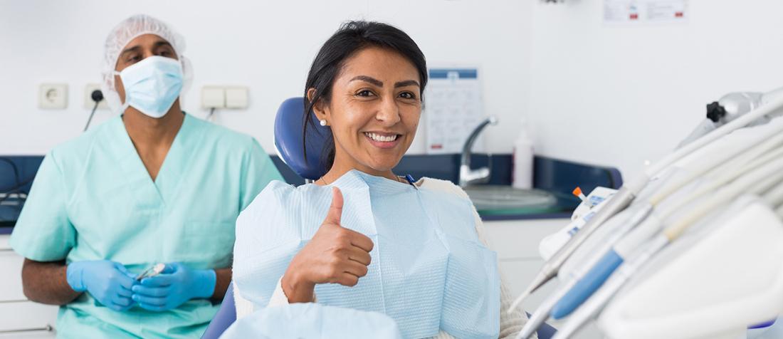 Female patient giving thumbs up in dental chair