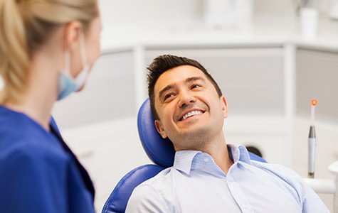 Man in dental chair leaning back and smiling