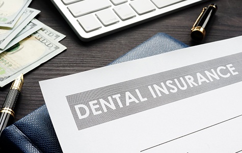 Dental insurance form on desk with money and keyboard