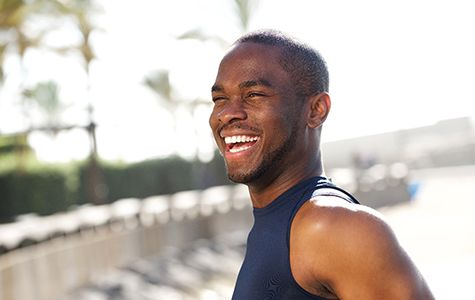 Man outside on a sunny day walking and smiling