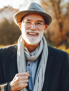 Older man smiling outdoors with scarf