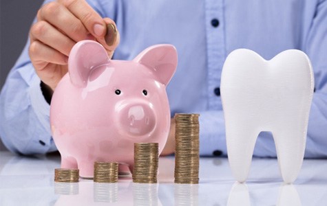 Close up of tooth piggy bank and coins