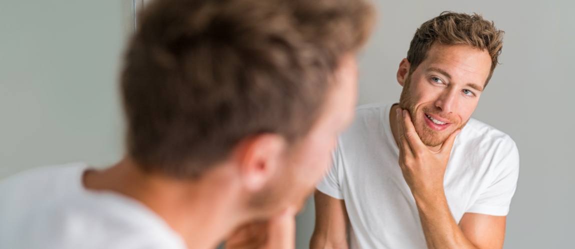 Young man looking at smile in mirror