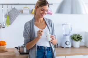 woman eating yogurt after dental implant surgery 